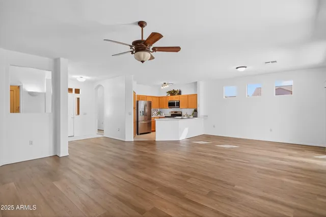 a view of empty room with wooden floor and ceiling fan