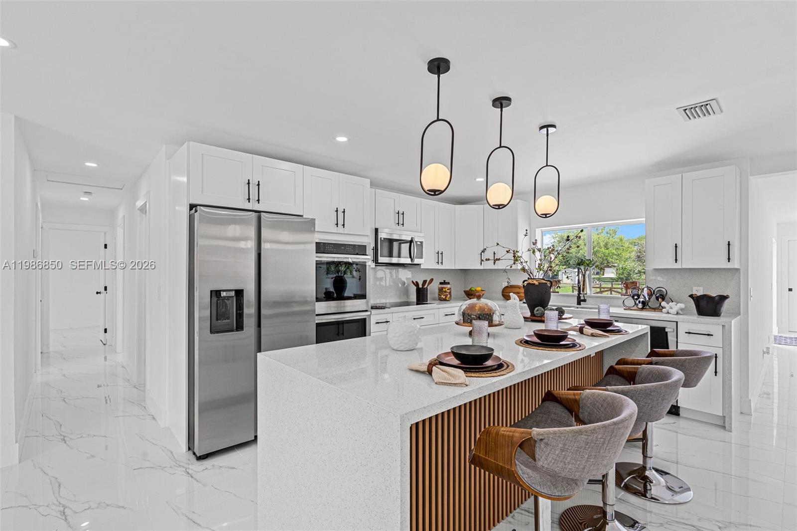4830 Southwest 188th Avenue Southwest Ranches, FL 33332 - Photo 19 of 58 a kitchen with stainless steel appliances granite countertop a sink a stove a refrigerator cabinets and chairs