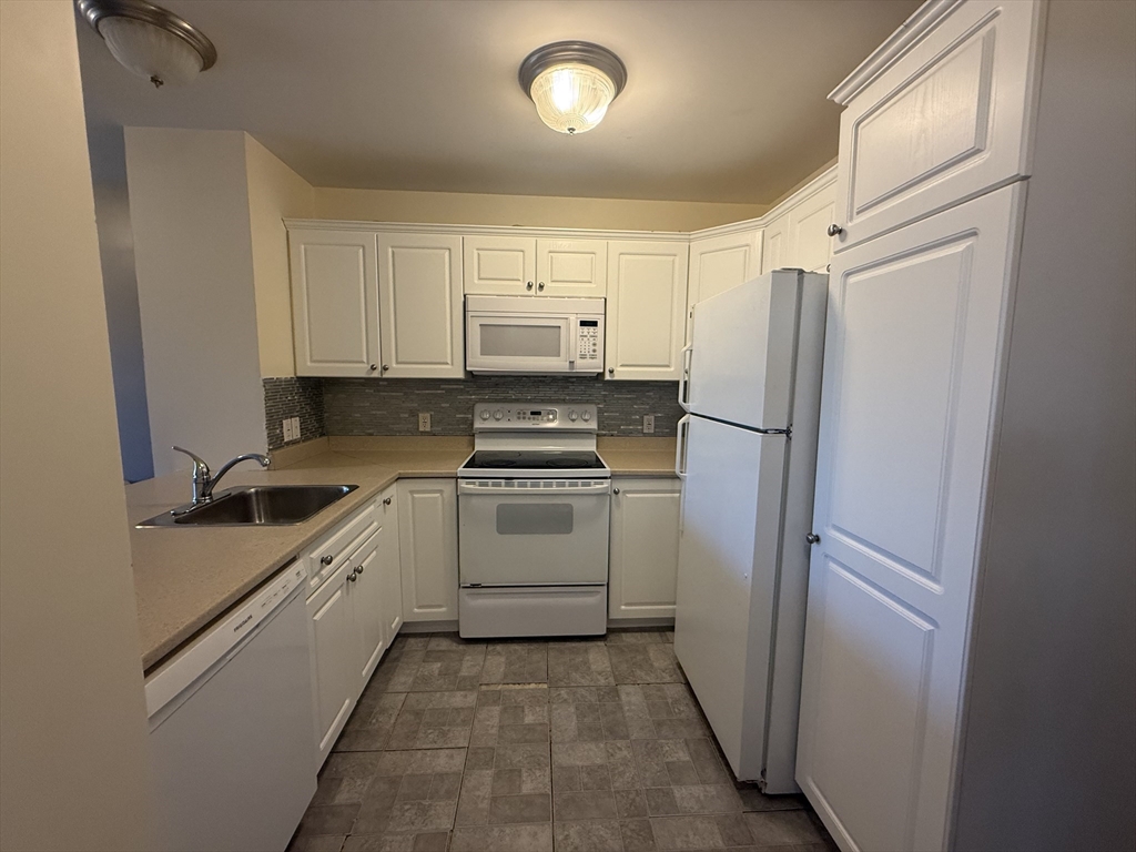 145 Bennington Street, Unit 307 Revere, MA 02151 - Photo 2 of 7 a kitchen with white cabinets and white appliances