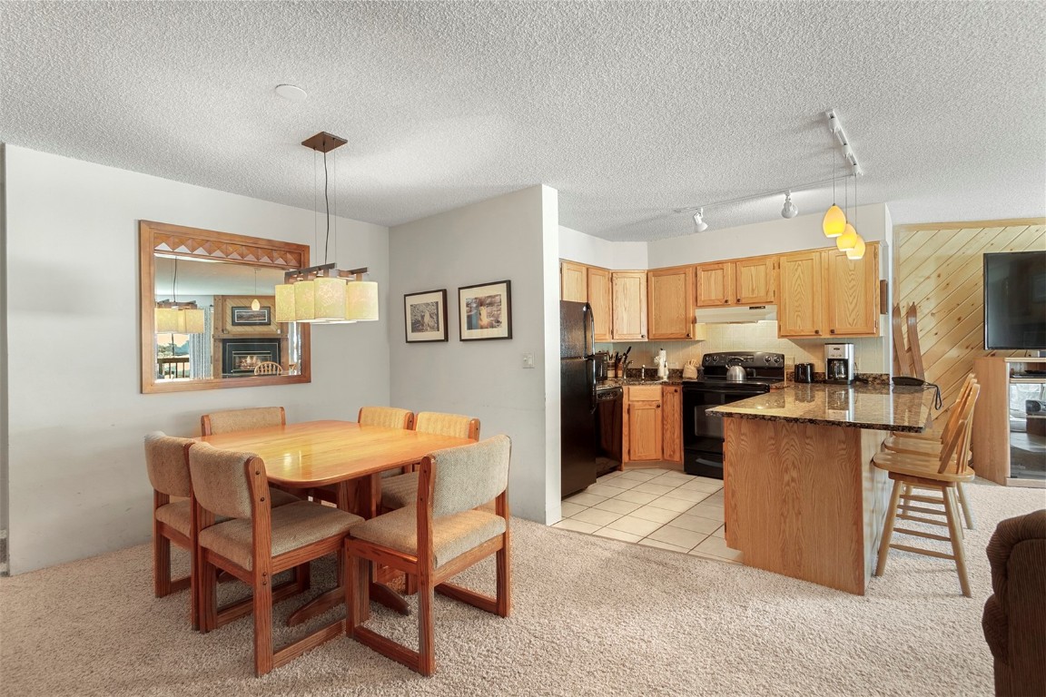 405 4 O Clock Road, Unit 12B Breckenridge, CO 80424 - Photo 11 of 27 a kitchen with stainless steel appliances kitchen island granite countertop a table chairs and a refrigerator