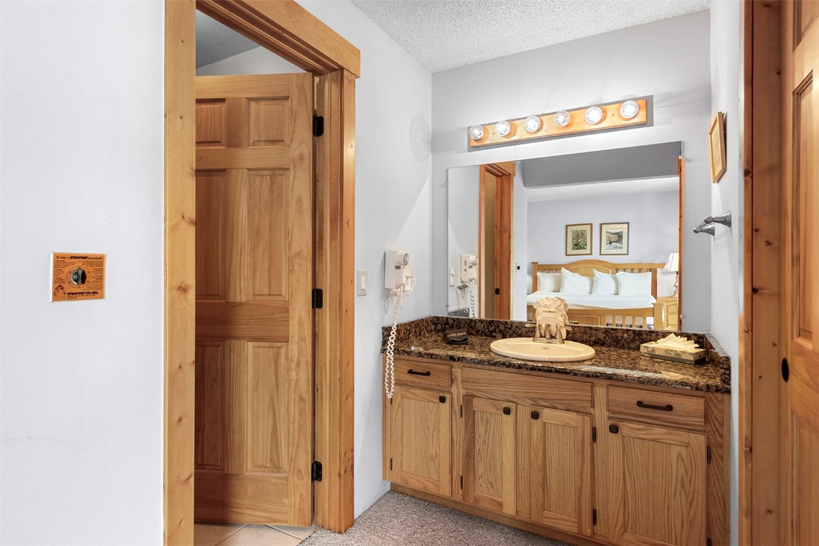 405 4 O Clock Road, Unit 12B Breckenridge, CO 80424 - Photo 14 of 27 a bathroom with a granite countertop sink and a mirror