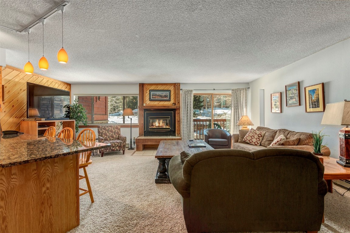 405 4 O Clock Road, Unit 12B Breckenridge, CO 80424 - Photo 5 of 27 a living room with furniture a fireplace and a flat screen tv