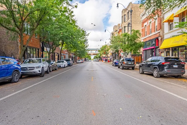 a view of a city street with a large building and a couple of cars parked on the road