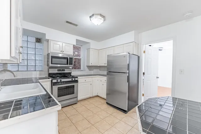 a kitchen with granite countertop a refrigerator and a stove top oven