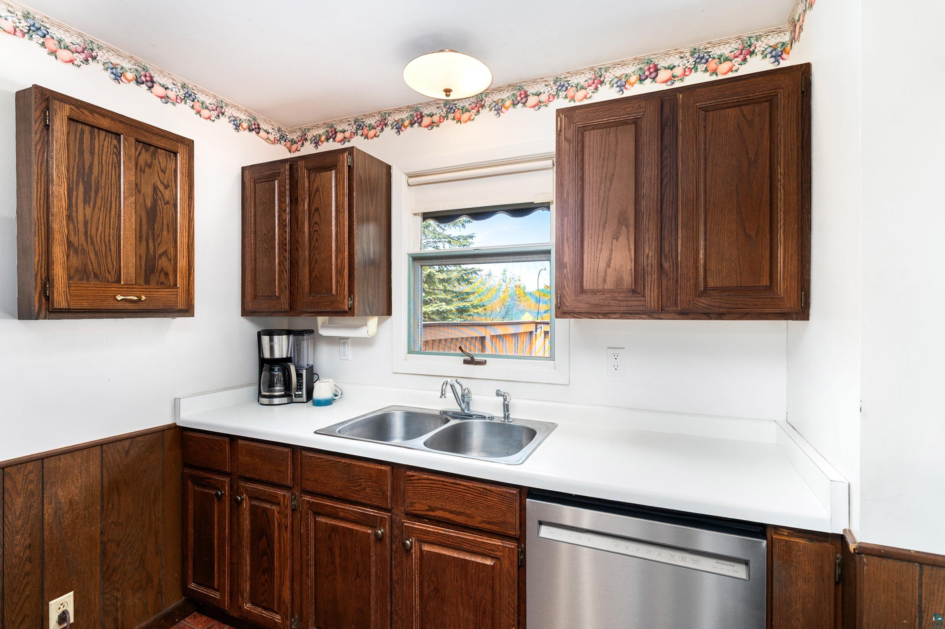 4808 Midway Road Duluth, MN 55811 - Photo 10 of 57 Kitchen workspace featuring wood cabinetry, white countertops, a double basin stainless steel sink, and a stainless steel dishwasher
