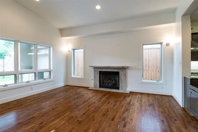 an empty room with wooden floor fireplace and windows