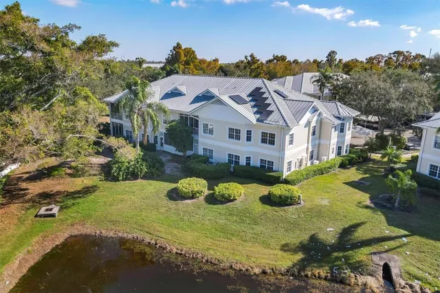 a view of a white house with a big yard plants and large trees