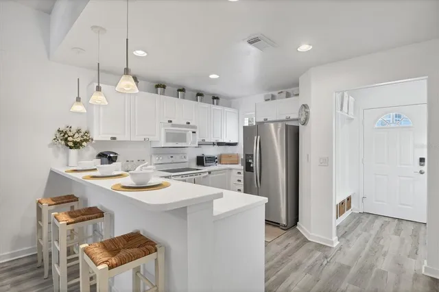 a kitchen with a refrigerator a sink dishwasher and white cabinets with wooden floor