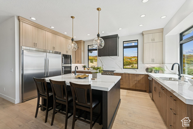 2280 East Outlaw Road, Unit 56 Kamas, UT 84036 - Photo 17 of 59 Kitchen with light stone counters, appliances with stainless steel finishes, a kitchen breakfast bar, a center island with sink, and recessed lighting