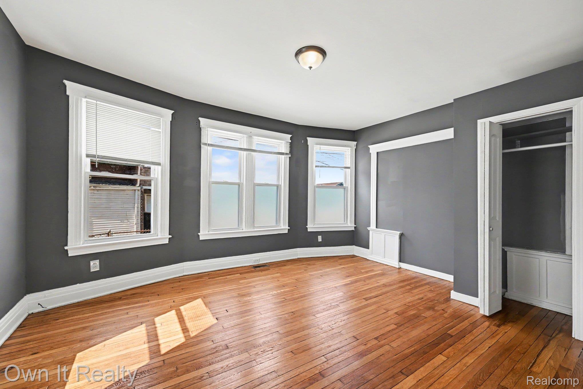 44 Maple Street River Rouge, MI 48218 - Photo 13 of 33 Wood-finish flooring, multiple windows, built-in closet with hanging rod, flush mount ceiling light, and detailed white trim work