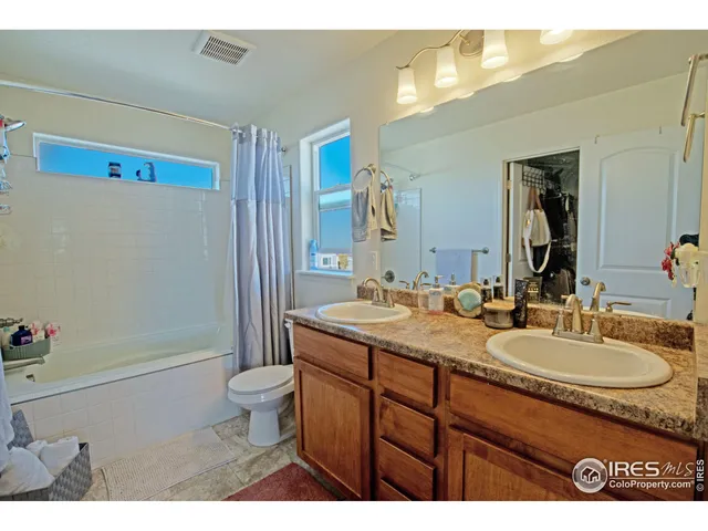 a bathroom with a granite countertop sink a toilet a mirror and shower