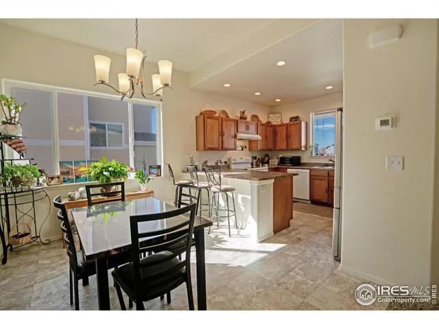 a kitchen with a dining table chairs and refrigerator