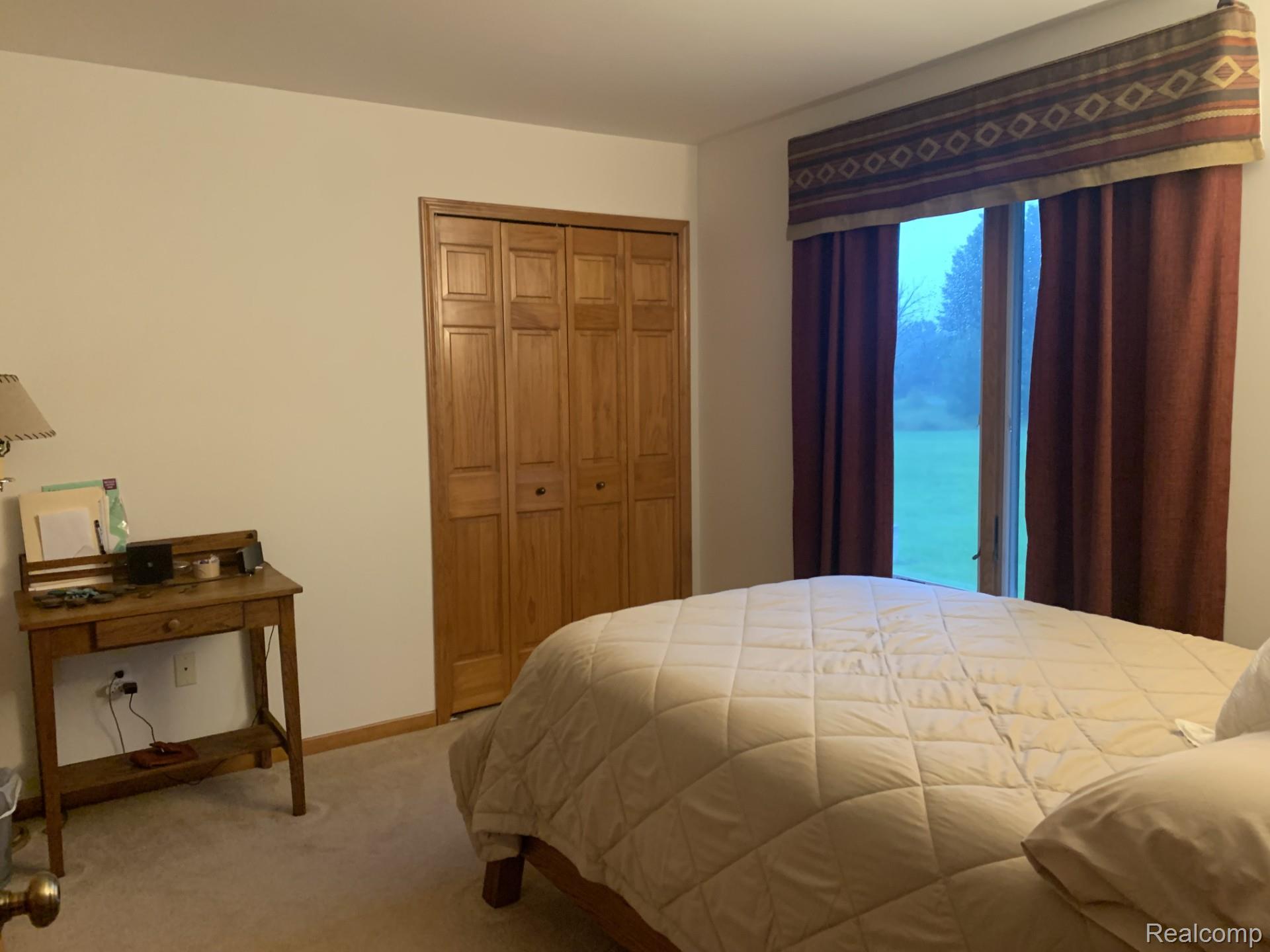 7542 Newberry Road Durand, MI 48429 - Photo 14 of 25 Light-colored walls with wood-finish bi-fold closet doors, wall-to-wall carpeting, and a window with a valance