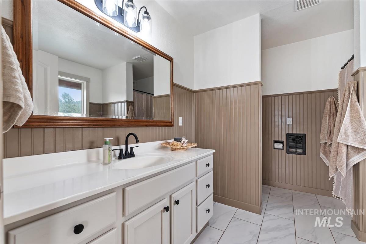 6 East Beck Road Garden Valley, ID 83622 - Photo 12 of 44 Full bathroom with a wainscoted wall, vanity, light marble finish floors, a shower with shower curtain, and wooden walls