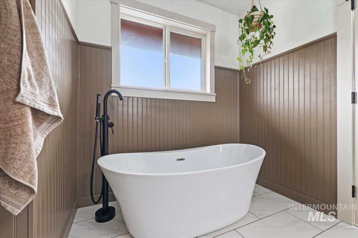 6 East Beck Road Garden Valley, ID 83622 - Photo 14 of 44 Full bathroom with wainscoting, a freestanding tub, light marble finish floors, and wood walls