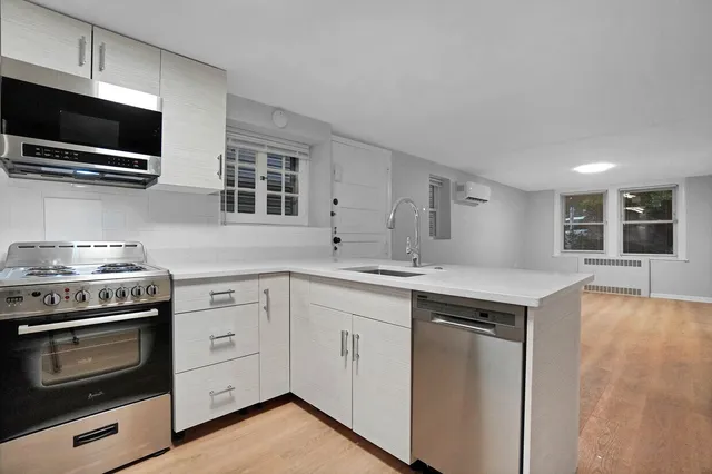 a kitchen with cabinets stainless steel appliances and wooden floor