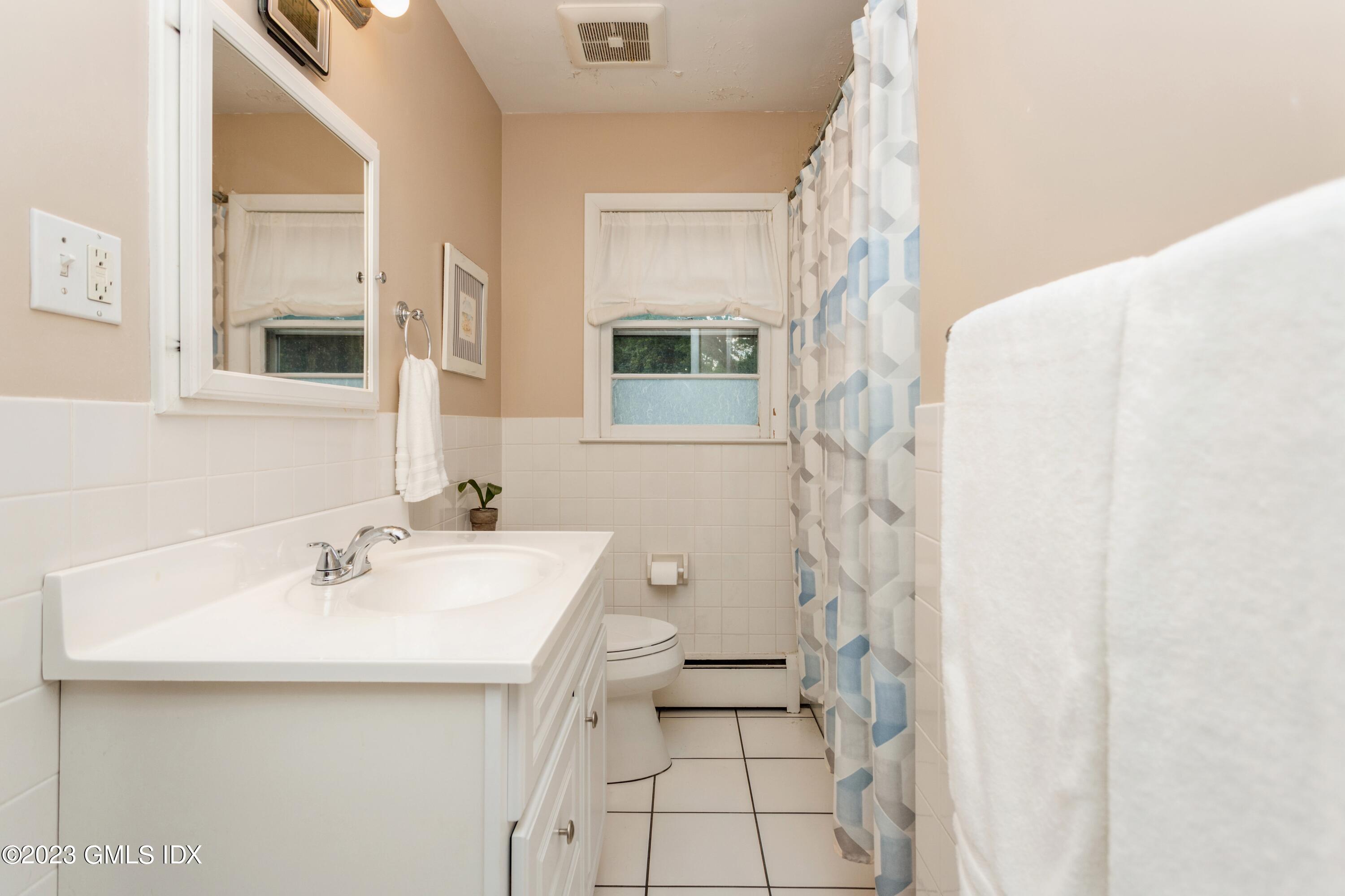 29 Dandy Drive Cos Cob, CT 06807 - Photo 10 of 17 a bathroom with a sink a toilet and shower curtain