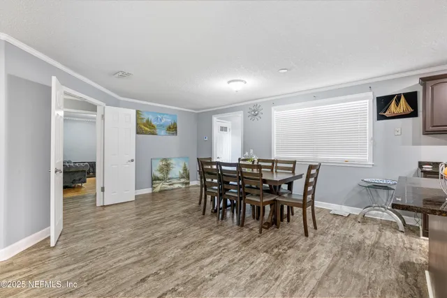 a kitchen with stainless steel appliances granite countertop a refrigerator a stove a sink a dining table and chairs with wooden floor