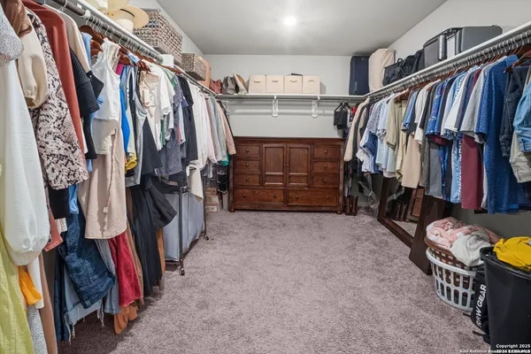 a view of walk in closet with clothes and shoes