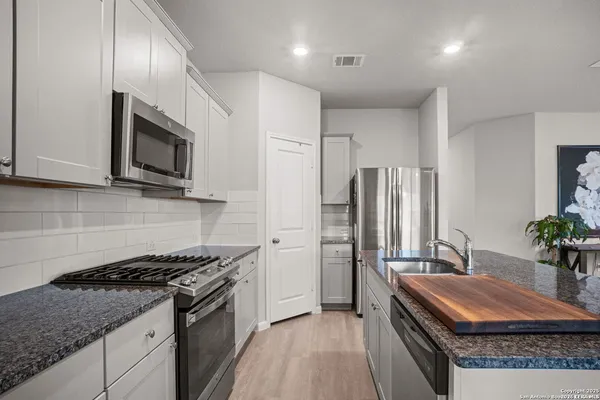 a kitchen with stainless steel appliances granite countertop a sink stove and refrigerator