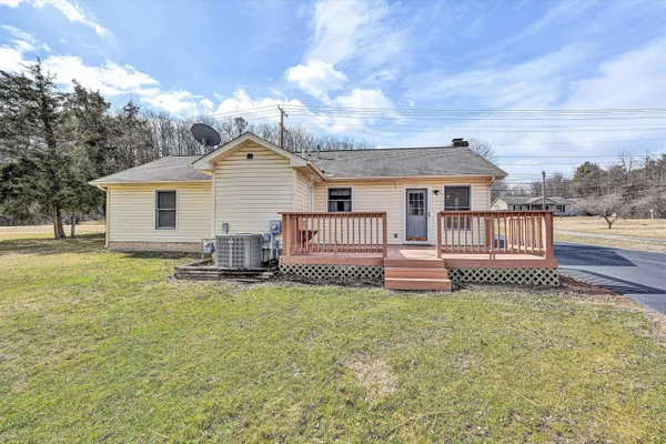 a view of a house with a yard and a large tree