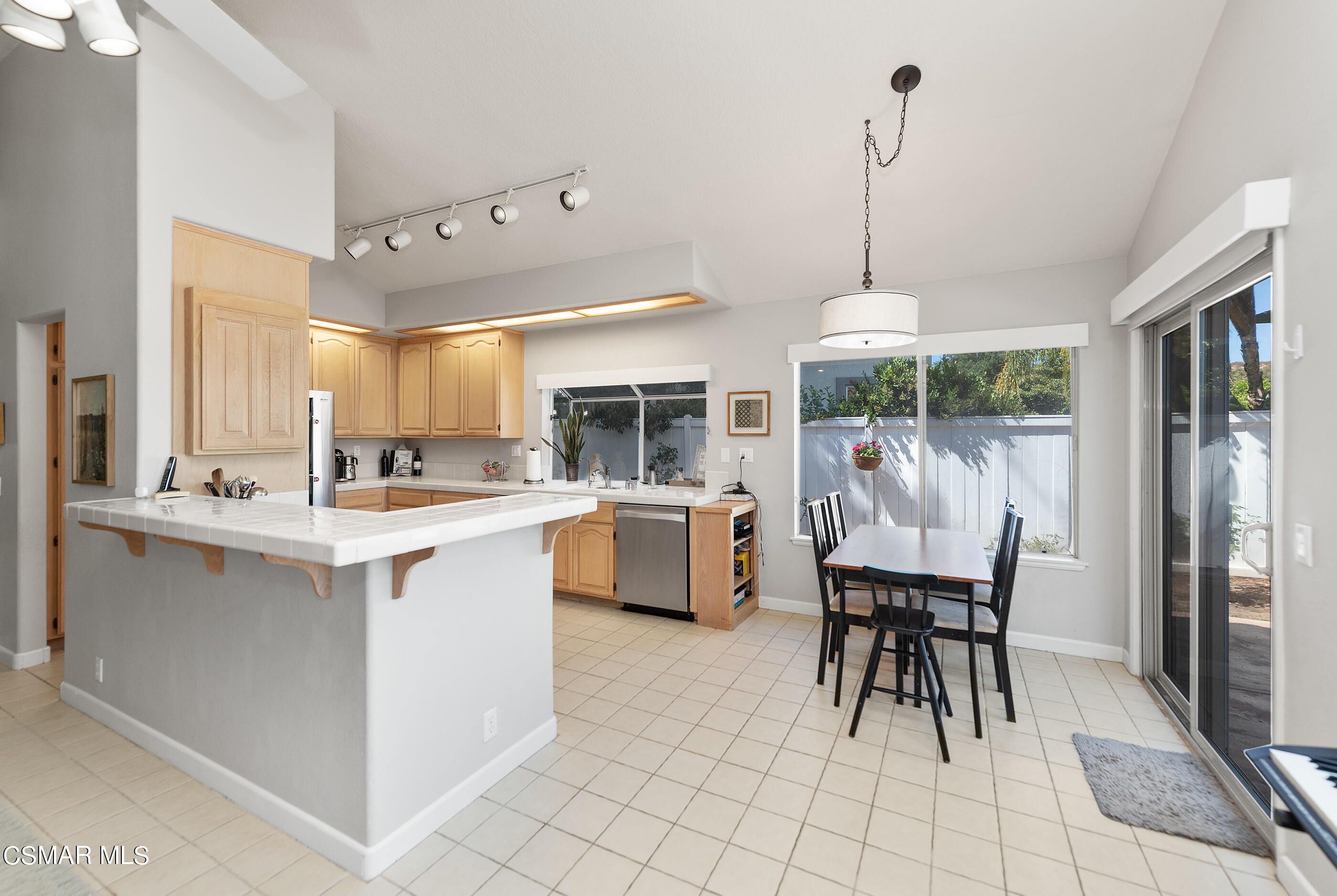472 Fresh Meadows Road Simi Valley, CA 93065 - Photo 13 of 33 a kitchen island with stainless steel appliances a dining table chairs and white cabinets