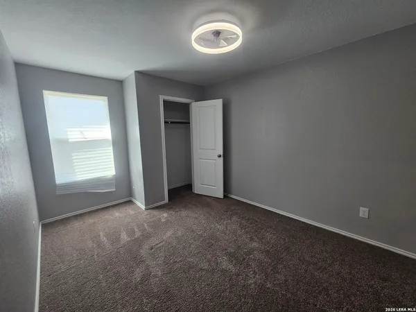 an empty room with a window and closet area