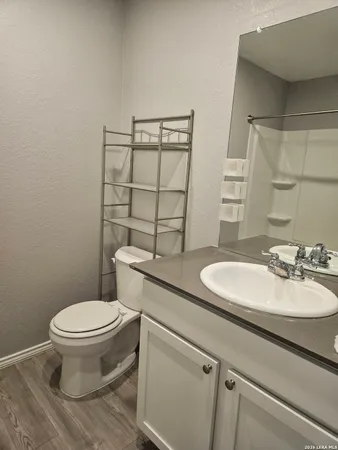 a bathroom with a granite countertop toilet sink and mirror