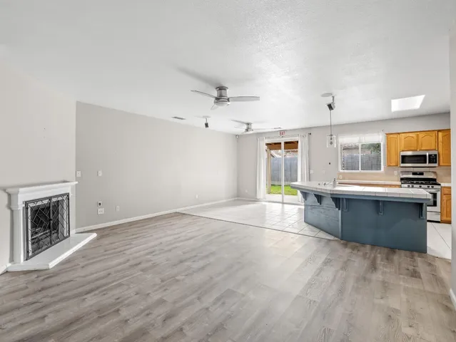 a large kitchen with granite countertop a stove top oven a sink dishwasher and a fireplace with wooden floor