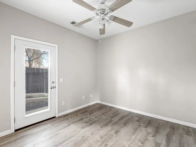 an empty room with a chandelier fan and windows