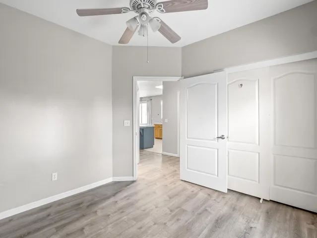 an empty room with a ceiling fan and wooden floor