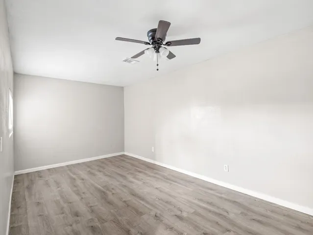 a view of a room with wooden floor and a ceiling fan