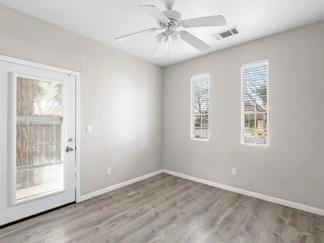 a view of empty room with wooden floor and fan