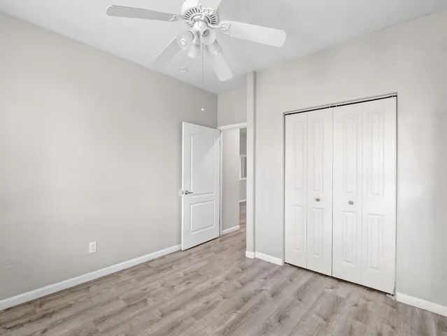 an empty room with wooden floor and fan