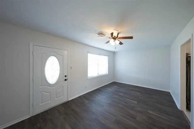 an empty room with wooden floor and a chandelier fan