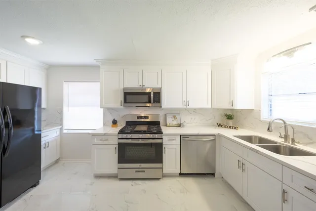 a kitchen with a sink white cabinets and stainless steel appliances