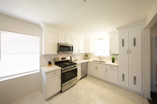 a kitchen with white cabinets and white appliances