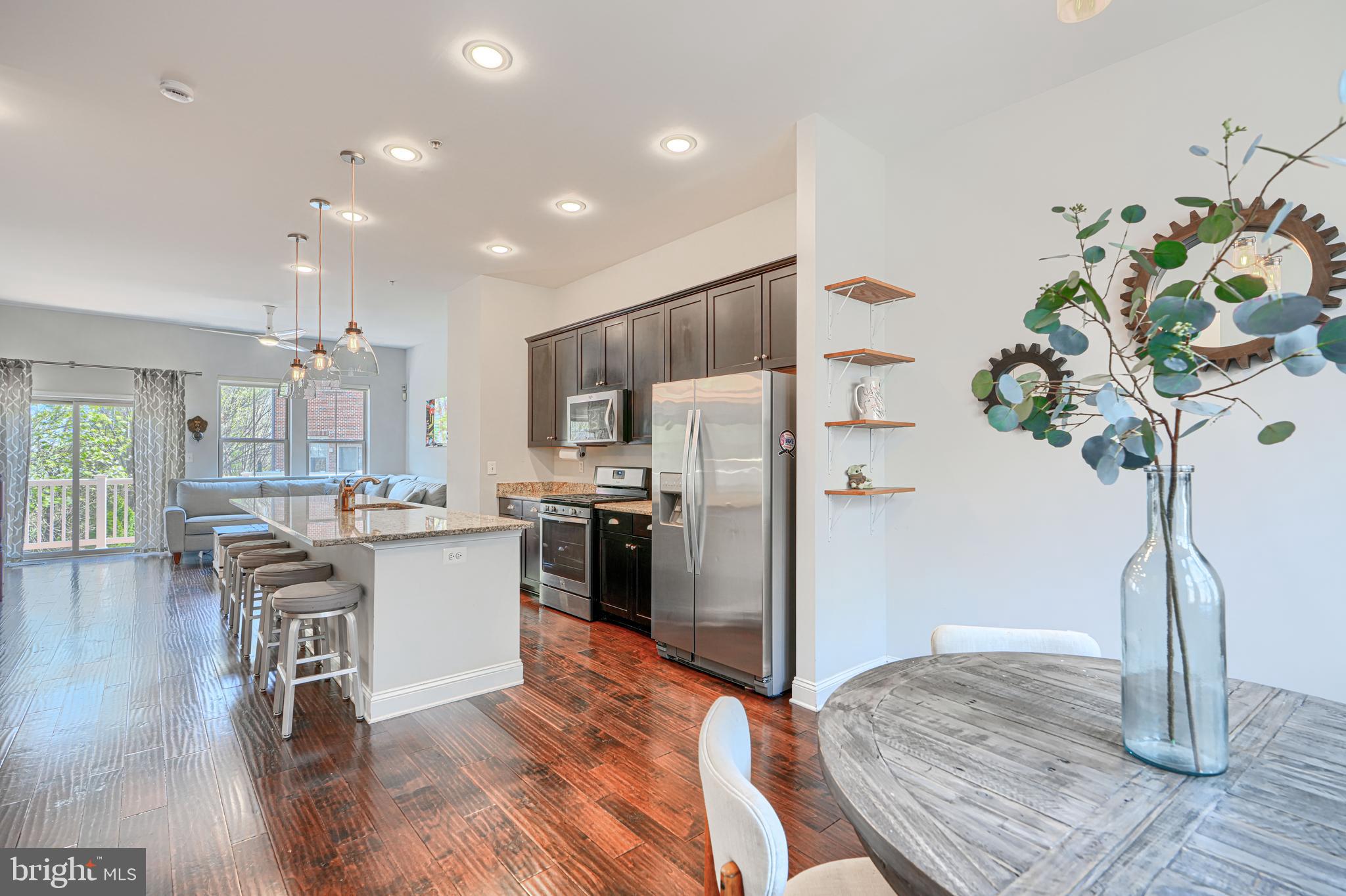a kitchen with stainless steel appliances granite countertop a refrigerator a stove a sink dishwasher and wooden floor