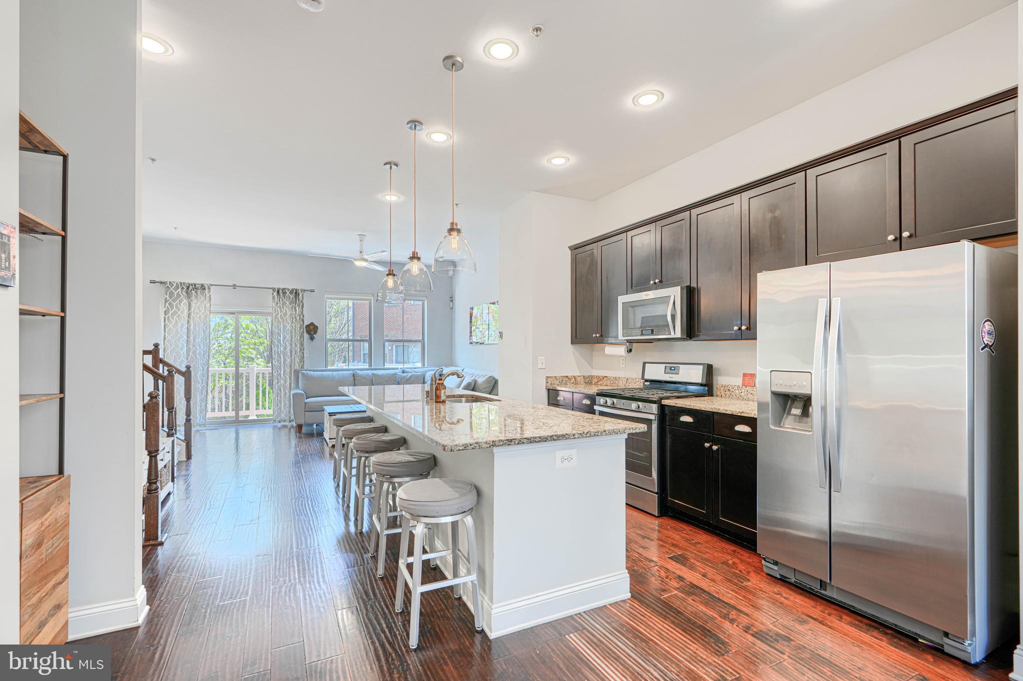 1309 Benjamin Street Baltimore, MD 21230 - Photo 22 of 60 a kitchen with kitchen island wooden cabinets a refrigerator a stove a sink a dining table and chairs