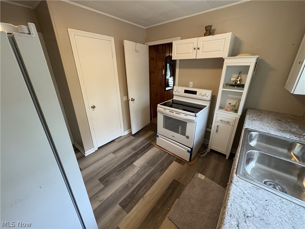 727 Wooster Road North Barberton, OH 44203 - Photo 36 of 37 Studio's Kitchen featuring wood-finish waterproof LVP flooring, white cabinetry, a dual basin stainless steel sink, speckled countertops, new fridge, and a white electric range with a black cooktop