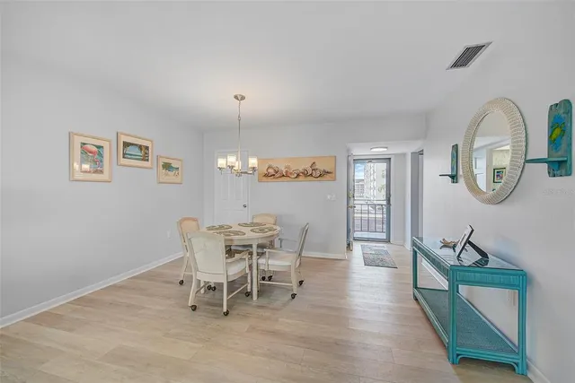 a dining room with wooden floor a glass table and chairs