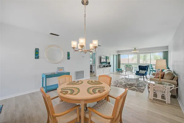 a view of a dining room with furniture a chandelier and wooden floor