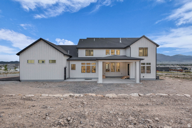 2828 Jojo Road Eagle Mountain, UT 84005 - Photo 54 of 63 Modern farmhouse architecture featuring white vertical siding, black-framed windows, a covered patio, and a dark shingled roof