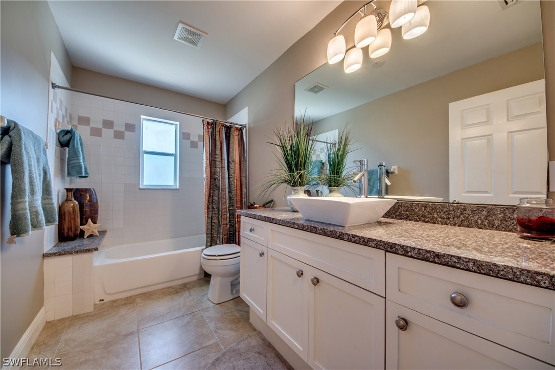 17517 Braddock Road Fort Myers, FL 33967 - Photo 26 of 33 a bathroom with a granite countertop sink a toilet a mirror and bathtub