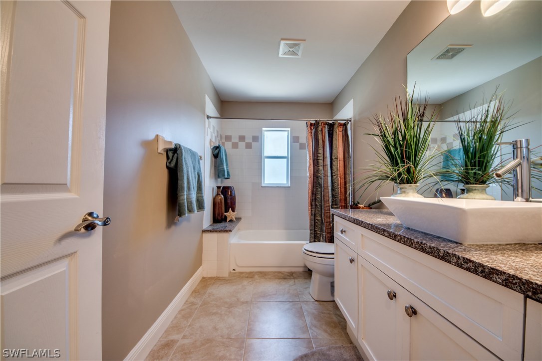 17517 Braddock Road Fort Myers, FL 33967 - Photo 27 of 33 a spacious bathroom with a granite countertop sink a toilet a mirror and shower