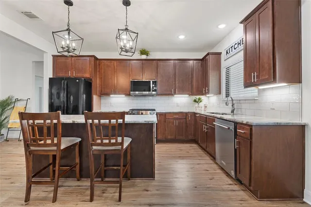 a kitchen with stainless steel appliances granite countertop a kitchen island a stove a sink dishwasher a dining table and chairs