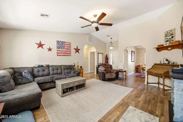 a living room with furniture kitchen view and a wooden floor