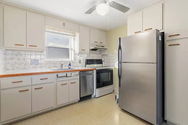a kitchen with stainless steel appliances granite countertop white refrigerator stove a sink and dishwasher with white cabinets