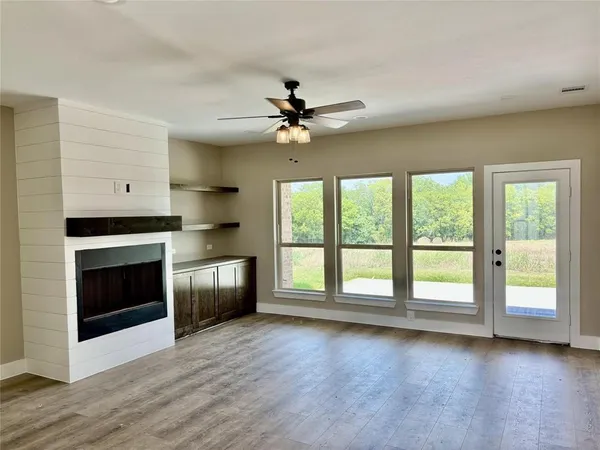 a view of empty room with a fireplace and wooden floor