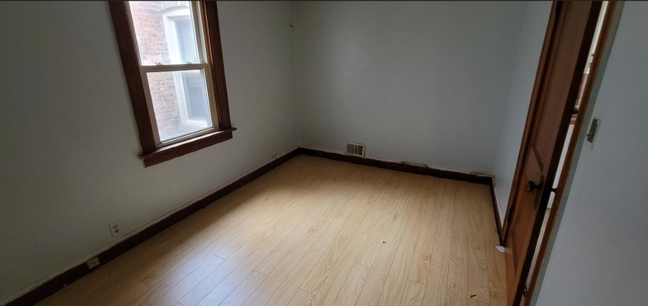 5604 South May Street Chicago, IL 60621 - Photo 5 of 9 a view of an empty room with wooden floor and a window